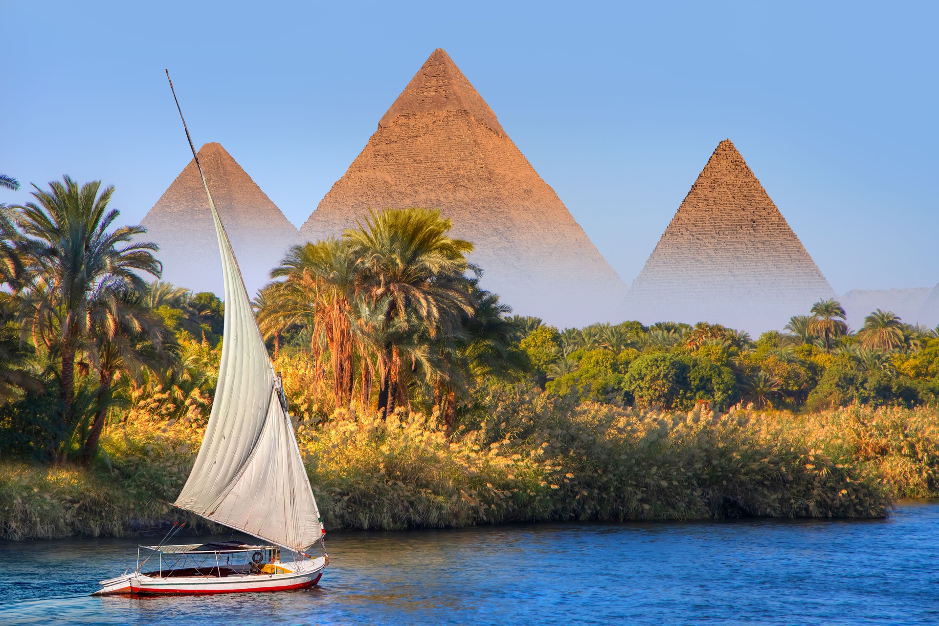Beautiful Nile scenery with traditional Felluca sailing boat in the Nile on the way to Giza pyramids - Cairo, Egypt